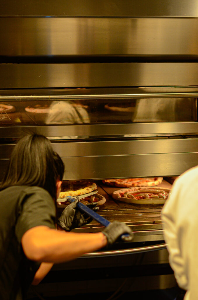 pizzaiolo che tira fuori la pizza dal forno di Salamensa